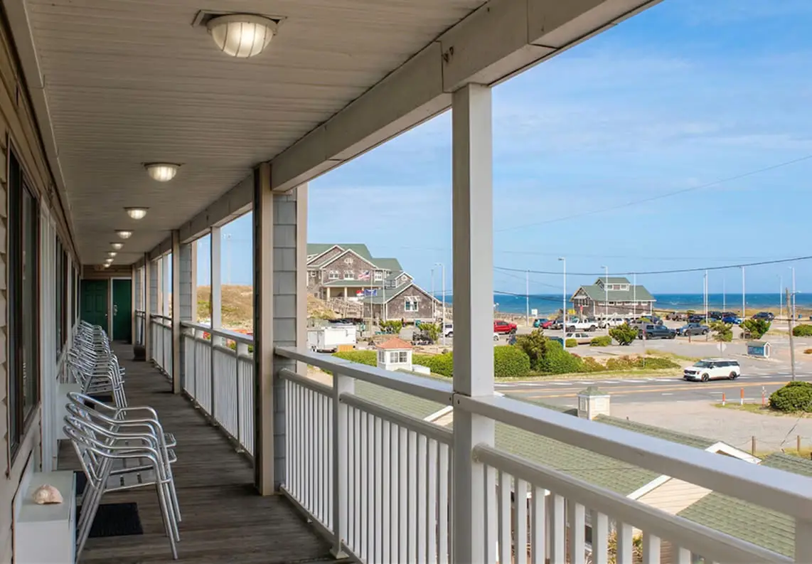 A covered upstairs walkway lined with chairs at Seahorse Inn & Cottages, looking out over the Beach Road towards the ocean