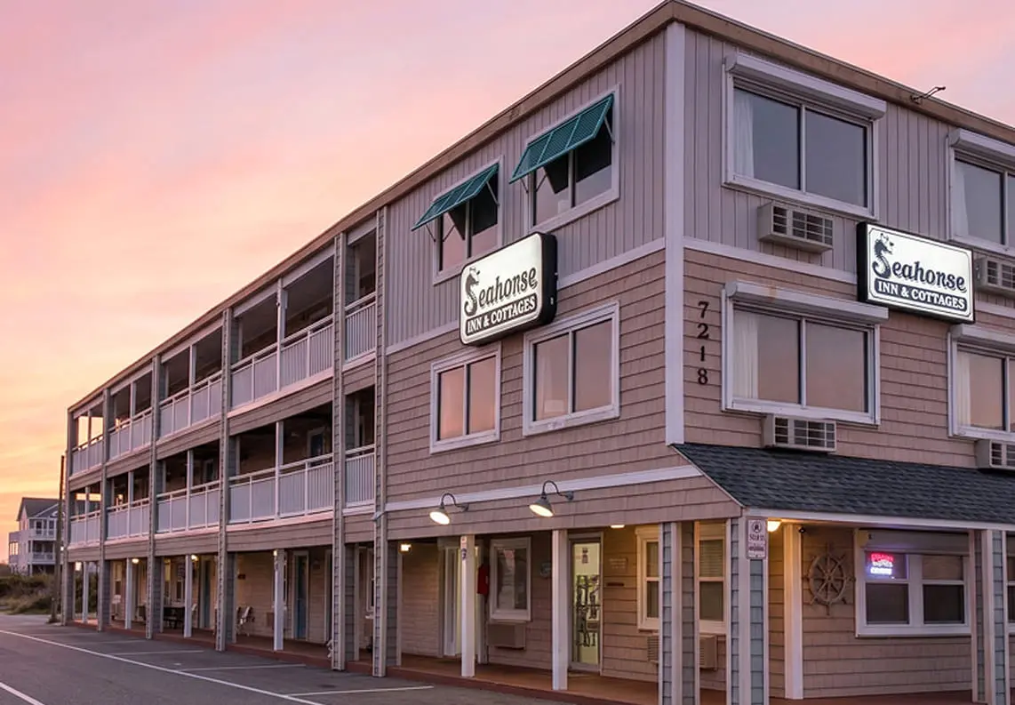 Seahorse Inn & Cottages at dusk, a three-storey shingled inn with lit signage and covered balconies, Nags Head, North Carolina
