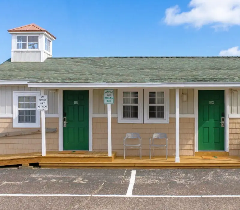 A row of single-storey cottages at Seahorse Inn & Cottages, with green doors, shingled roofs and small cupolas, separate from the main inn building