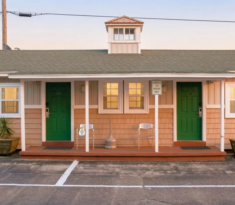 A single-storey cottage at Seahorse Inn & Cottages, with green doors, a shingled roof and a small cupola, set apart from the main inn building