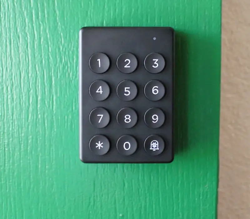 A black keypad with numbers 0-9, an asterisk, and a bell symbol is mounted on a green wooden surface