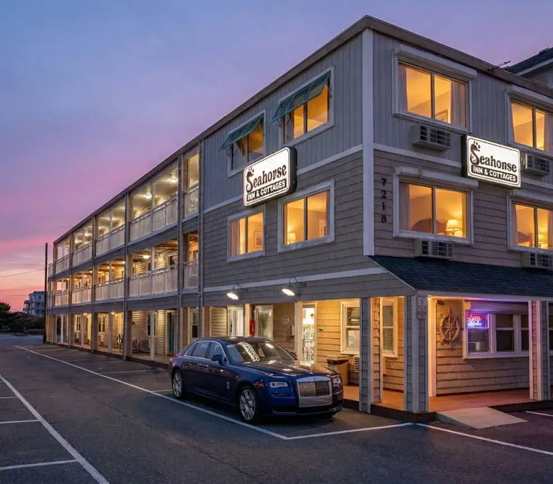 A two-storey building with "Seahorse Inn & Cottages" signs, a blue car parked outside and a purple sunset sky