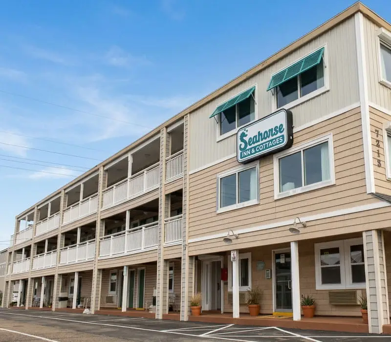The Seahorse Inn & Cottages building has three storeys of rooms with balconies and a ground floor with entrances and windows, under a blue sky