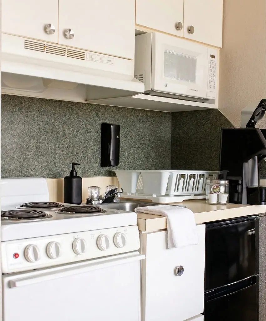 A kitchenette with a white electric range, microwave and sink in the Premium Room at Seahorse Inn & Cottages